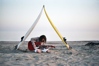 Cloud is the man sitting in the gray plays the guitar on the beach
